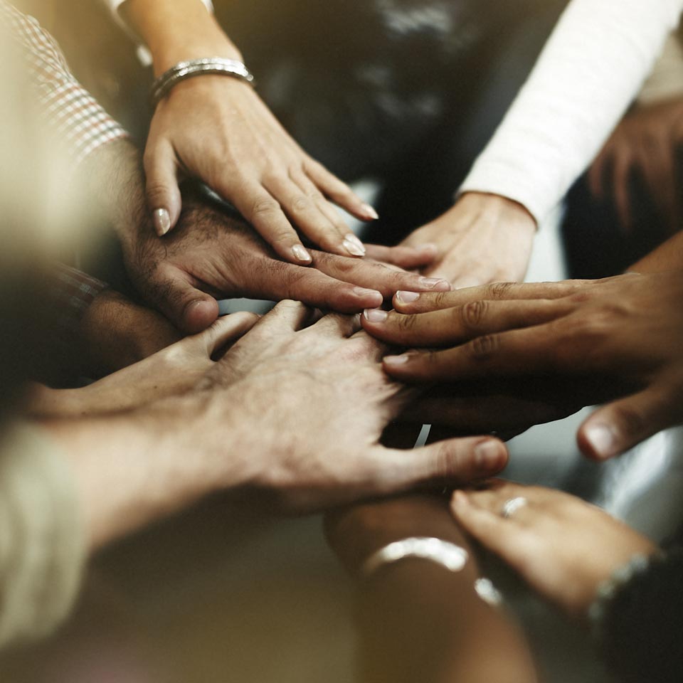 A circle of diverse hands putting in for a team cheer
