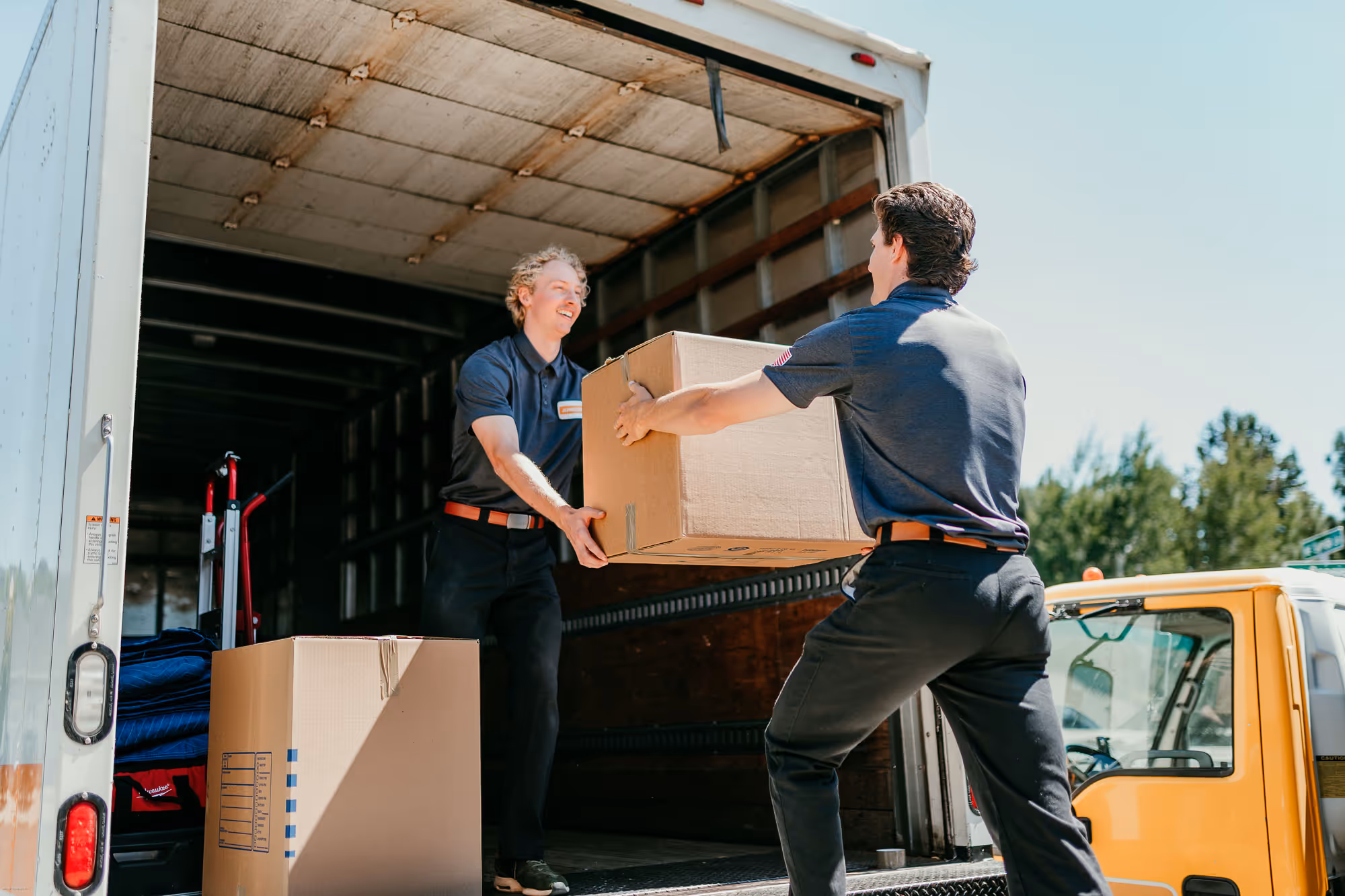 Local moving team in Bend are transporting a box onto the moving truck.