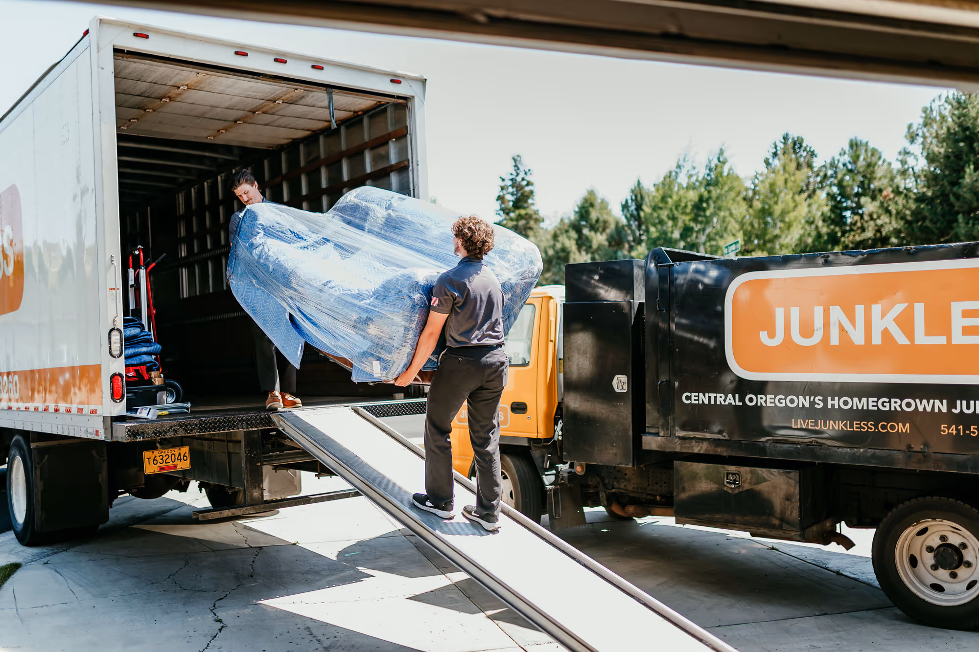 Two movers providing small moving services in Bend by moving a couch onto the moving truck.