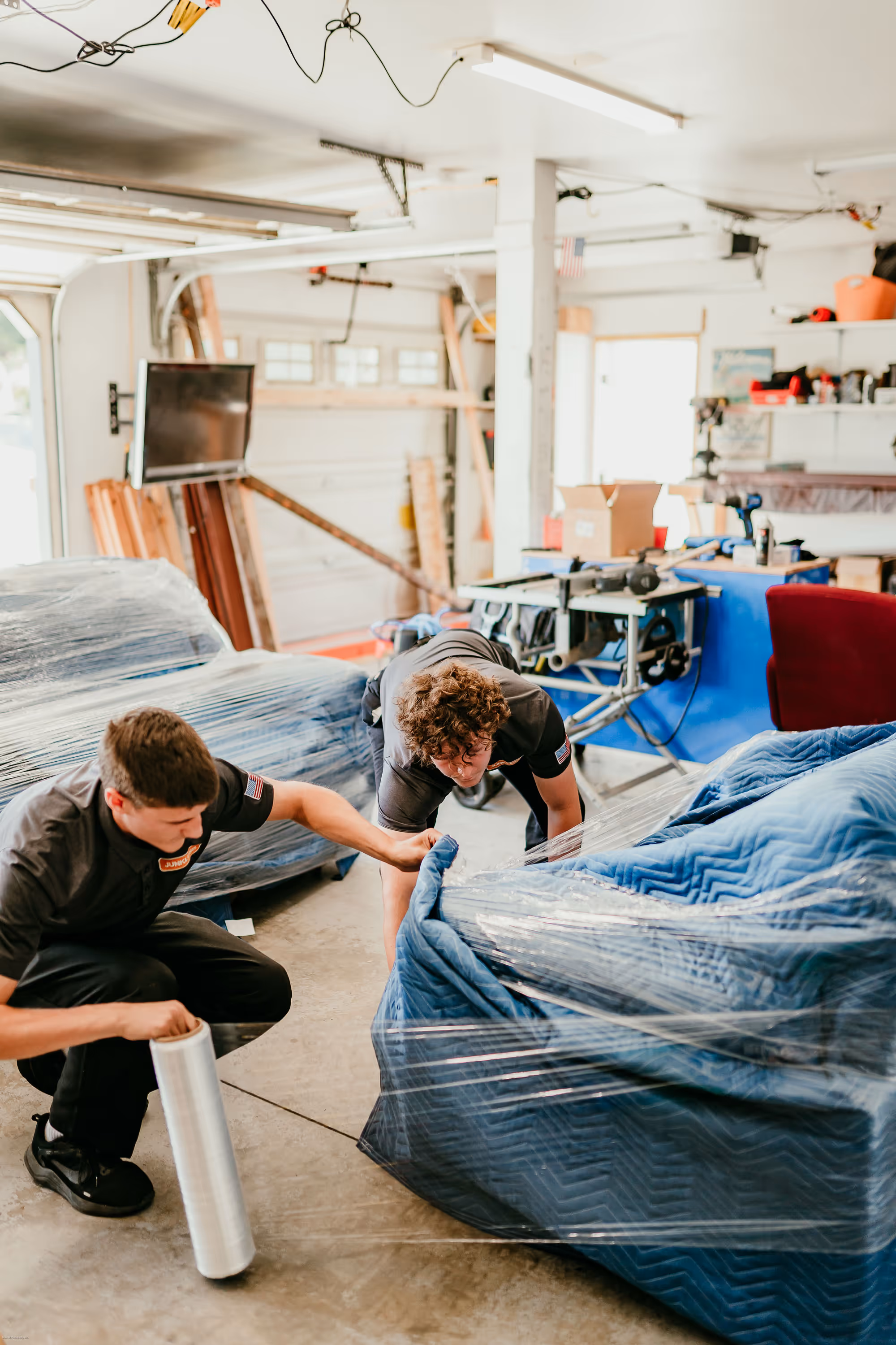 An example of local moving services and careful packing services with two professional movers in Bend packaging a sofa.