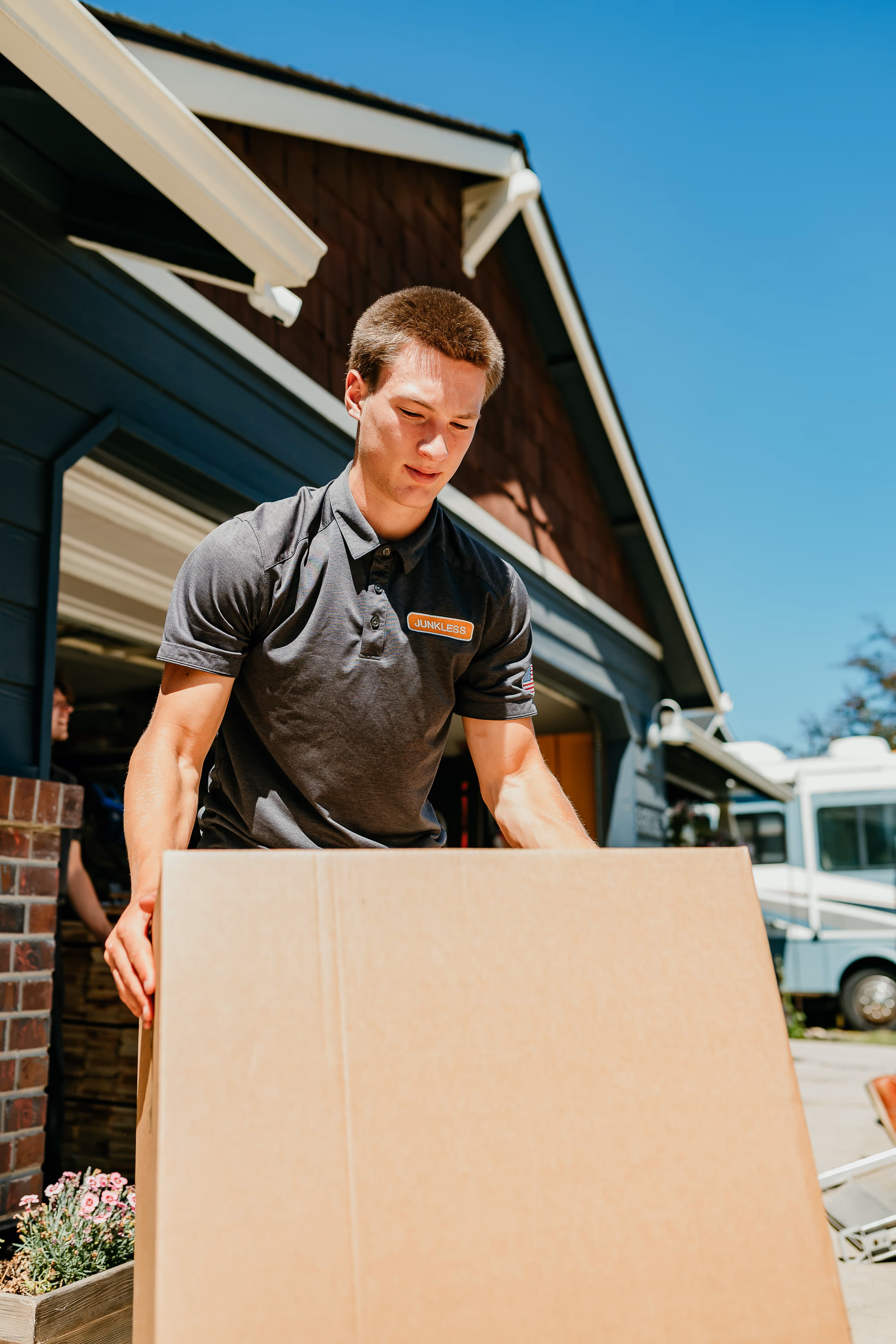 Live Junkless mover is transporting box into moving vehicle. We can help with heavy items.