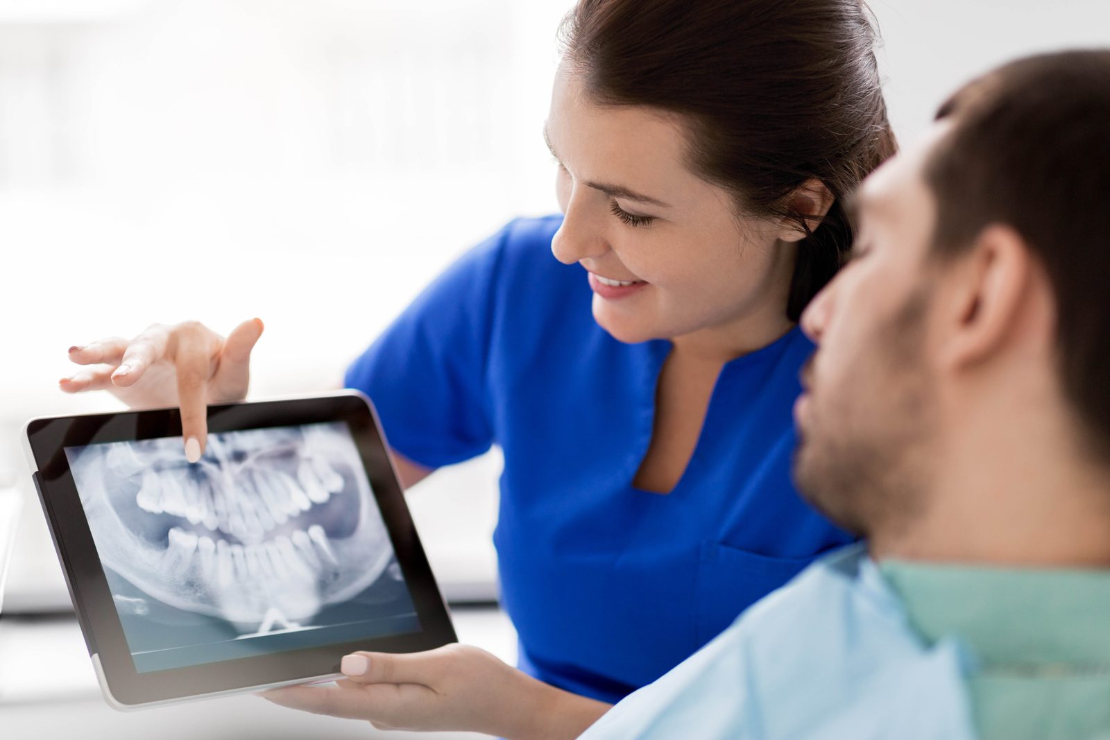Dentist reviewing a panoramic X-ray with a patient while planning dental implant treatment in Houston, TX
