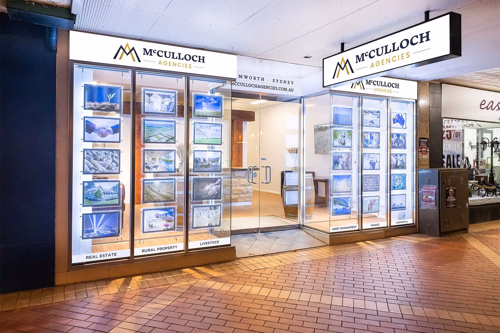 Brightly lit real estate storefront with illuminated displays of property listings