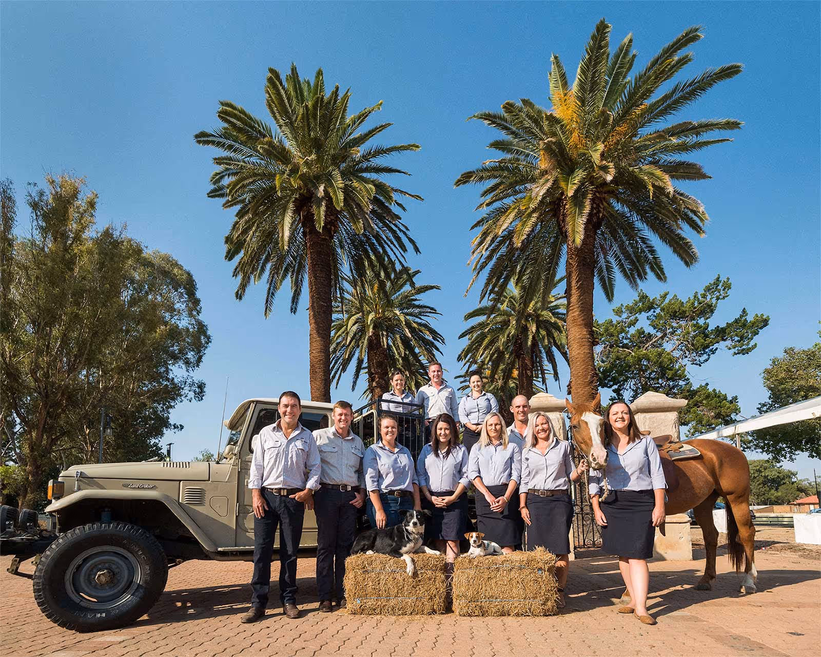 A group of people in matching attire poses by a vintage jeep