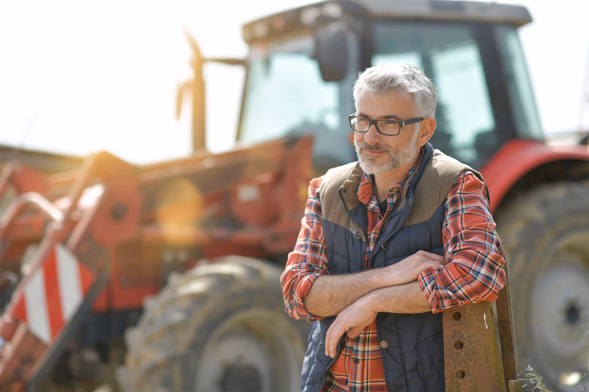 A middle-aged man with gray hair and glasses leans on a fence post