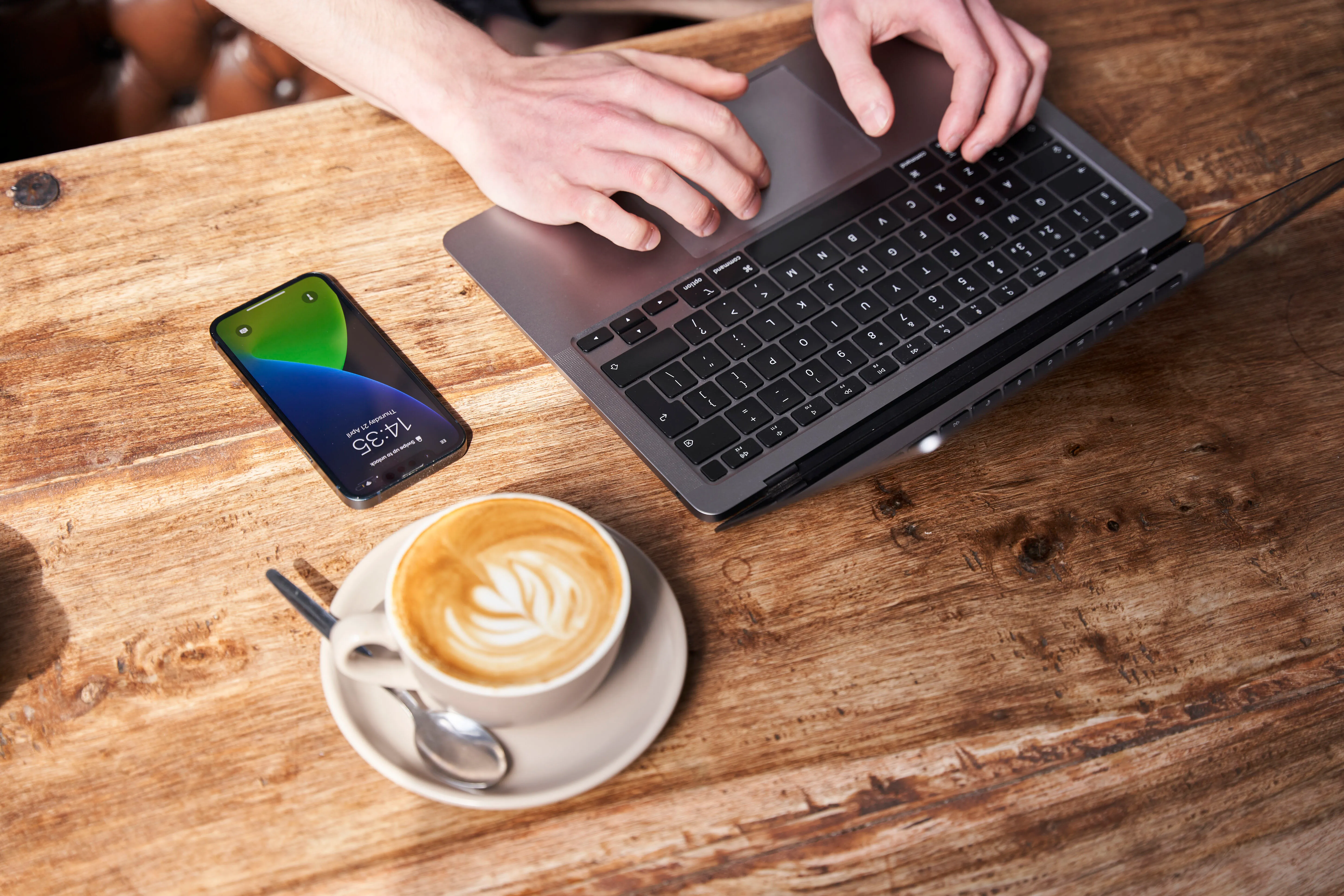 UX designer sitting with a coffee doing competitor research on his laptop