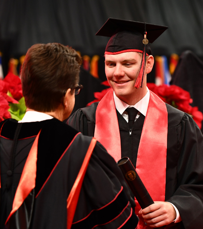 Graduate receiving their diploma and shaking hands with school administrator 