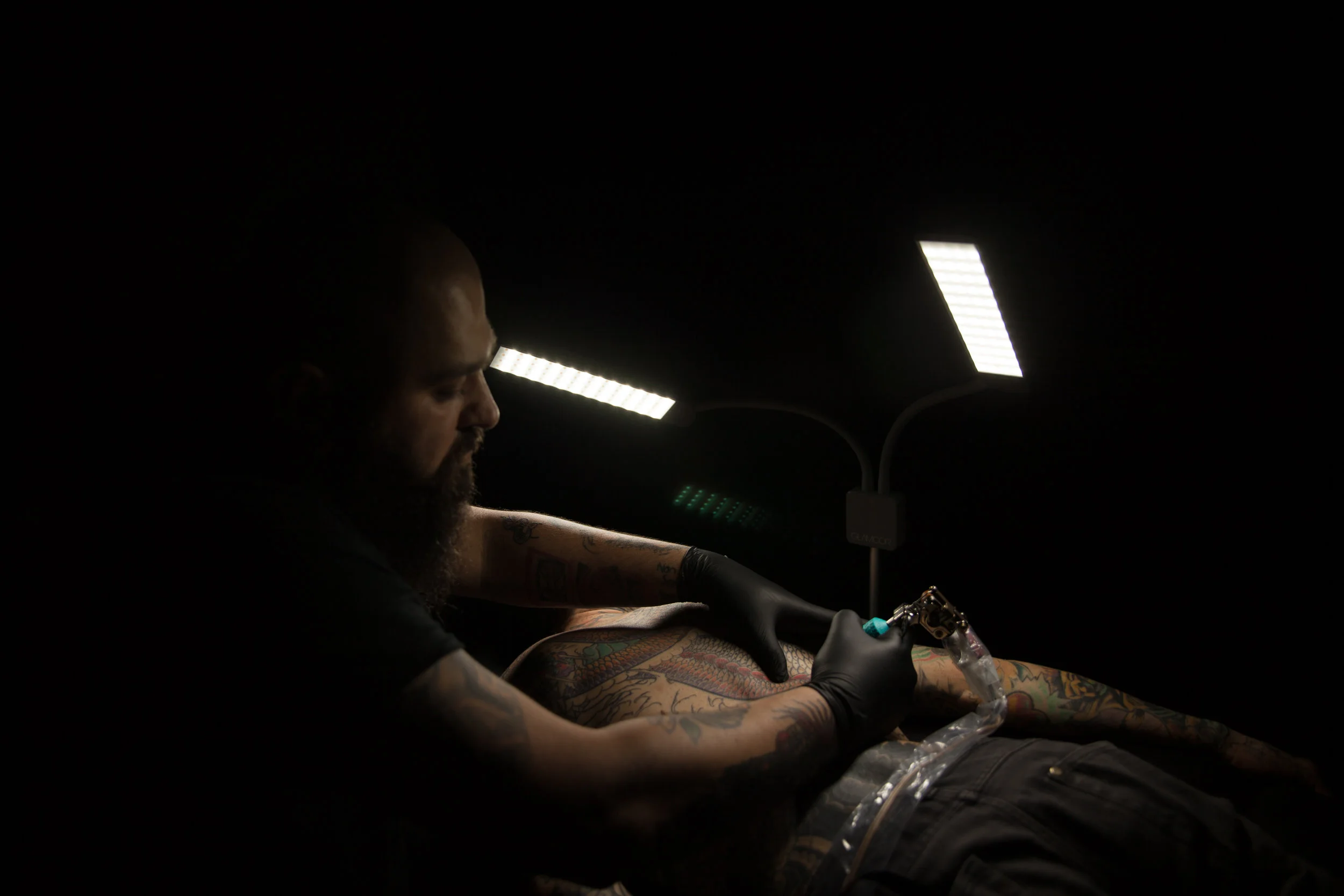 Tattoo artist giving a tattoo in a dark room