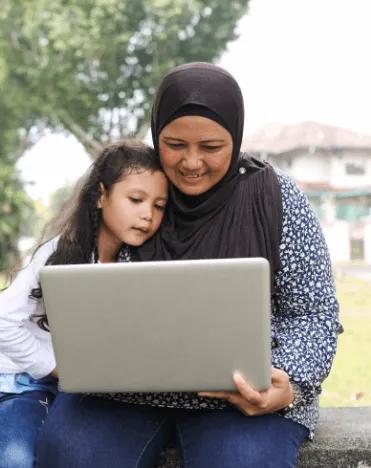 A mother and daughter look over a laptop