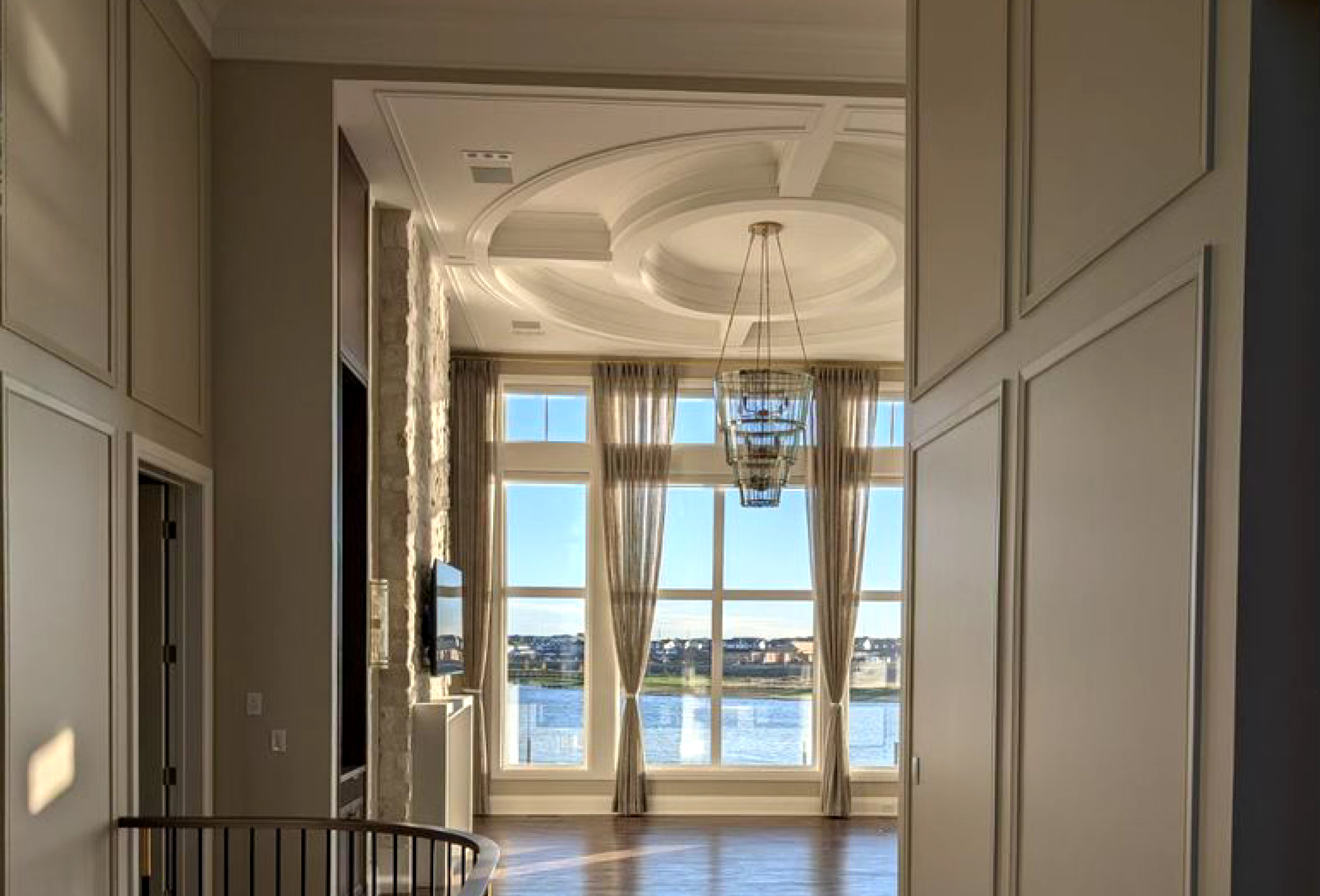 An empty dining room with a circular ceiling detail, window, and chandelier