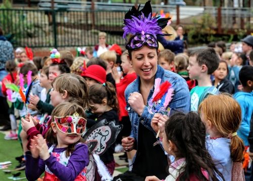 Teacher in fancy dress, dancing with students.