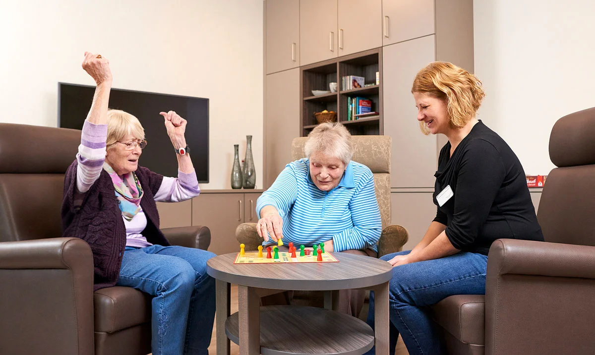 Mitarbeiterin spielt mit zwei Bewohnerinnen ein Brettspiel