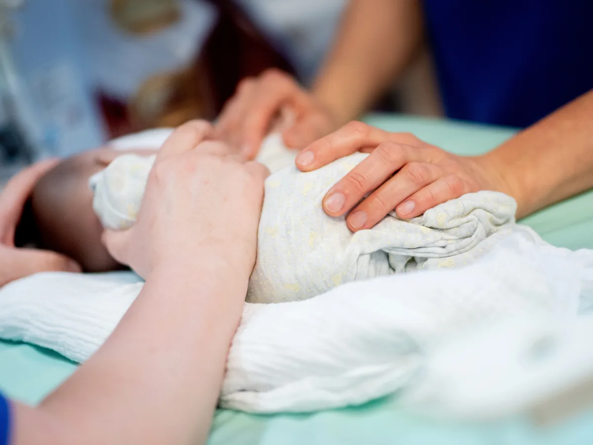 Pflegefachkraft leitet Eltern bei der Versorgung ihres Kindes an