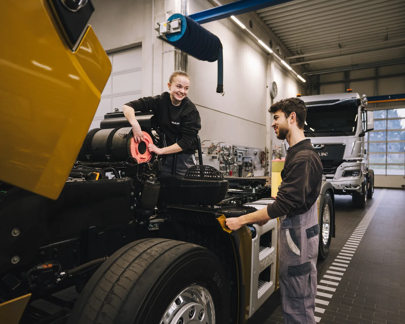Teamleiter und Kollegin bei der Arbeit an einem MAN Lkw-Fahrgestell in der Werkstatt