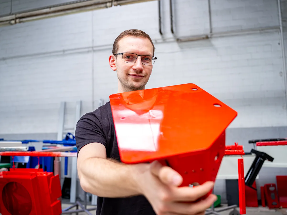 Mitarbeiter mit frisch lackiertem Bauteil