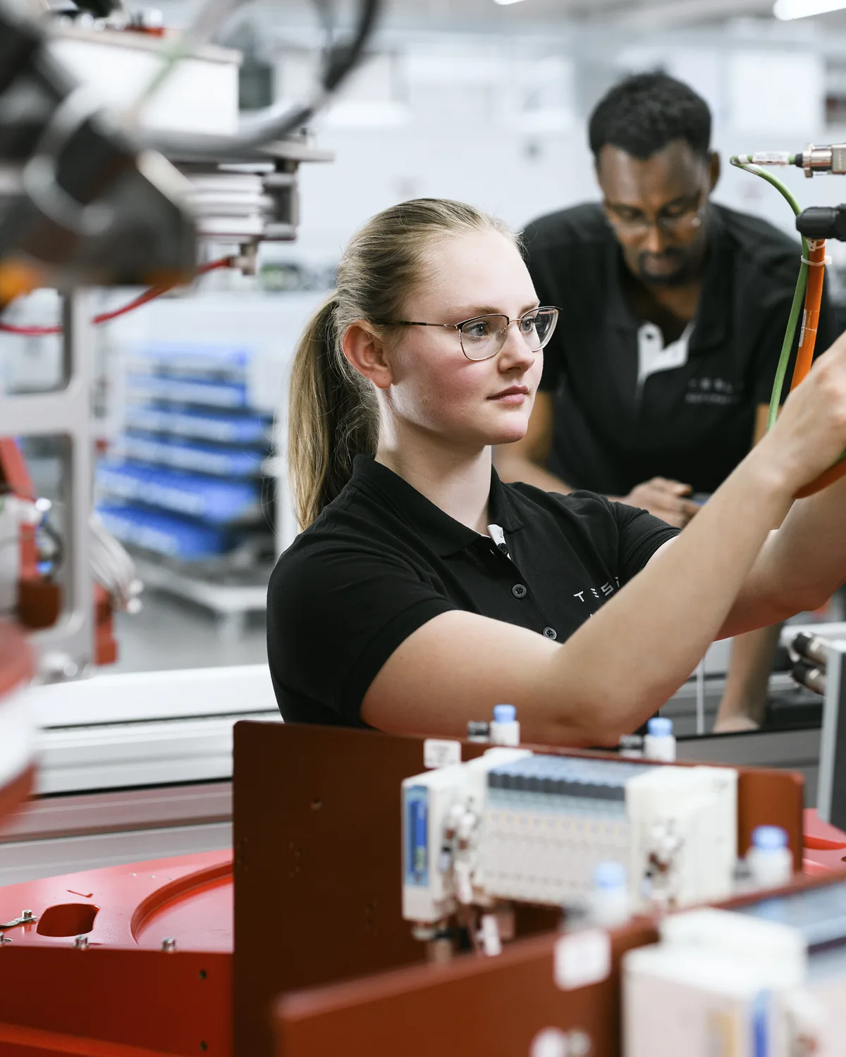 Mitarbeiterin von Tesla Automation an einer Montageanlage
