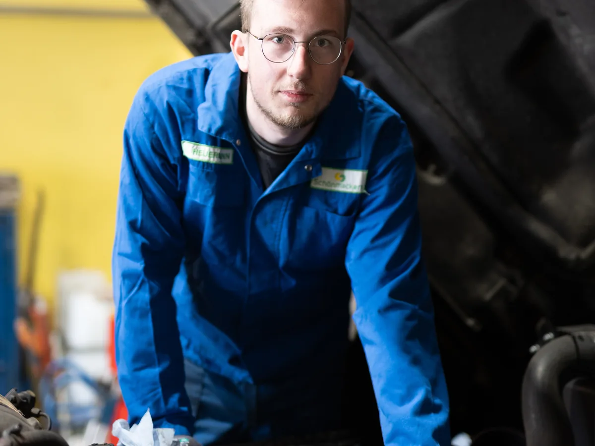 Mechaniker bei der Arbeit unter der Motorhaube eines Entsorgungsfahrzeugs