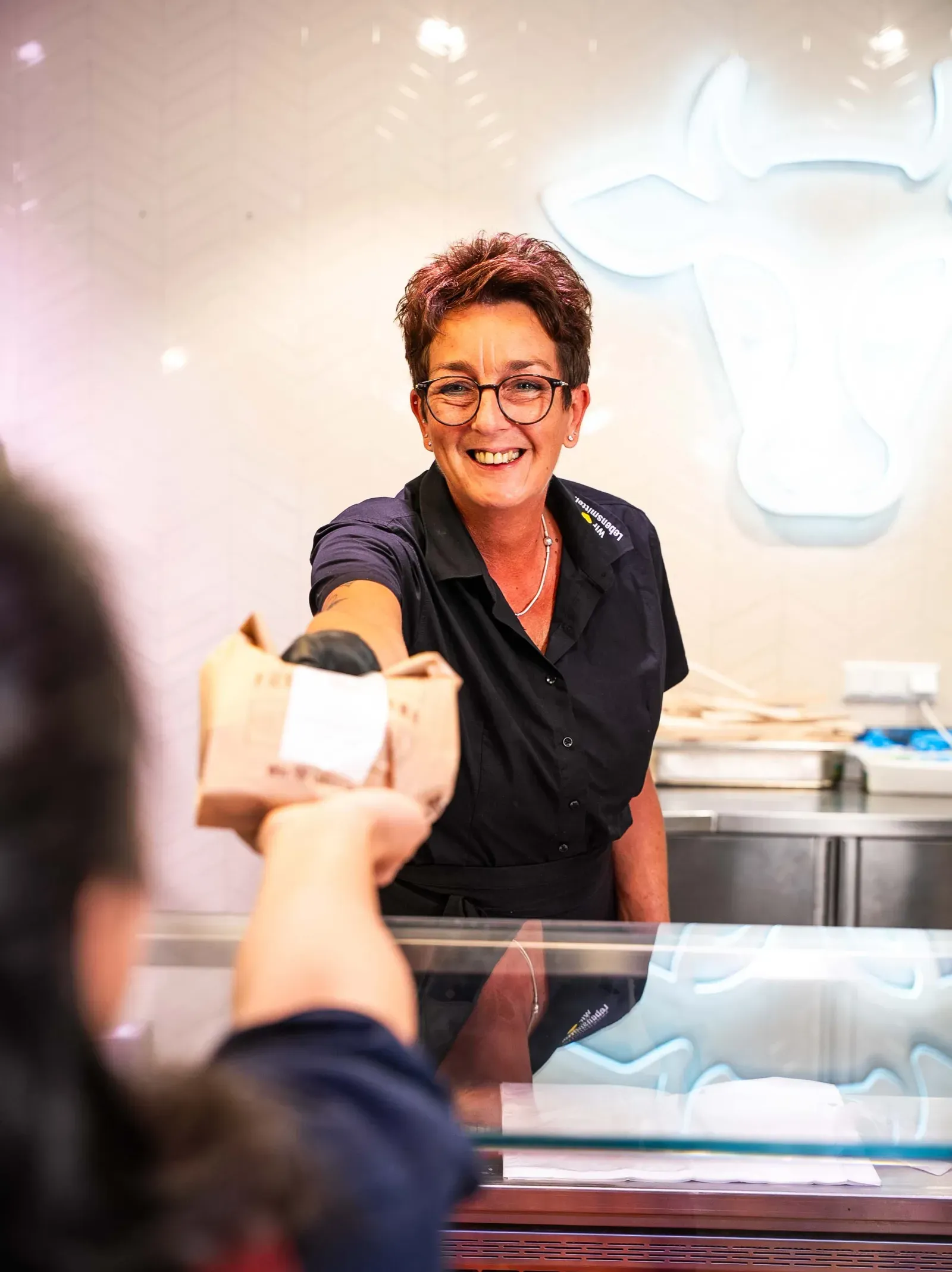 Mitarbeiterin übergibt Ware an der Frischetheke