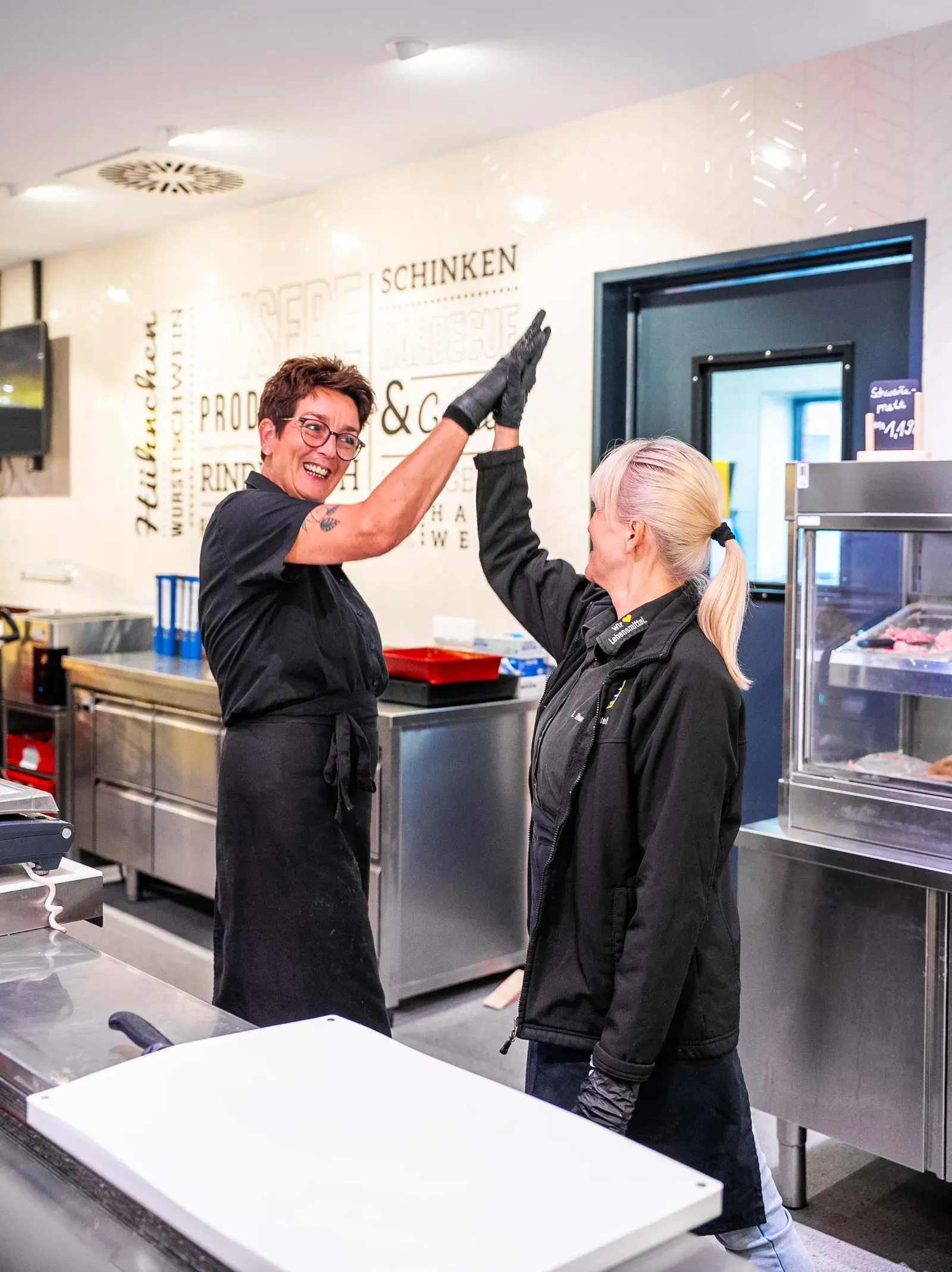 Team gibt sich High Five an der Fleischtheke