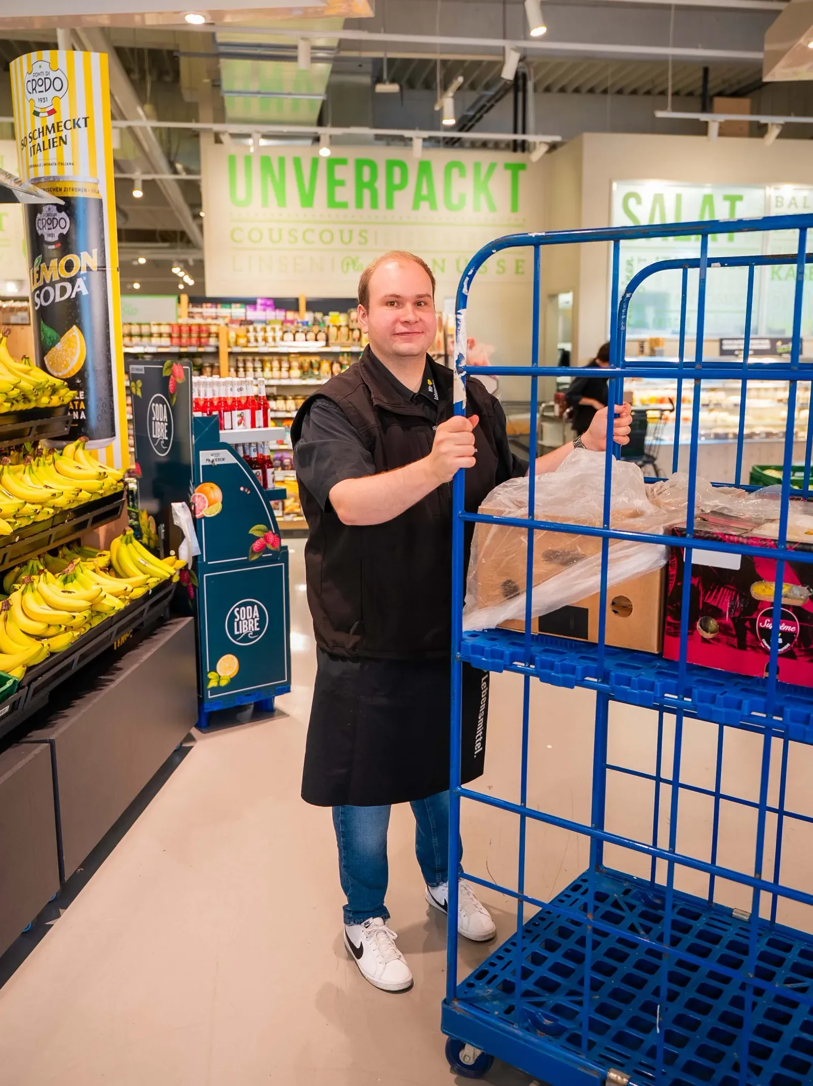 Mitarbeiter mit Rollcontainer im Unverpackt-Bereich