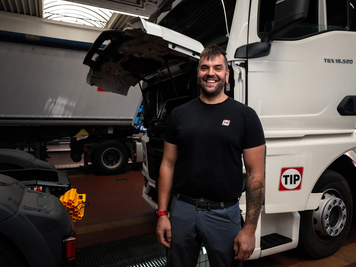 Lachender TIP Mechatroniker vor dem Lkw
