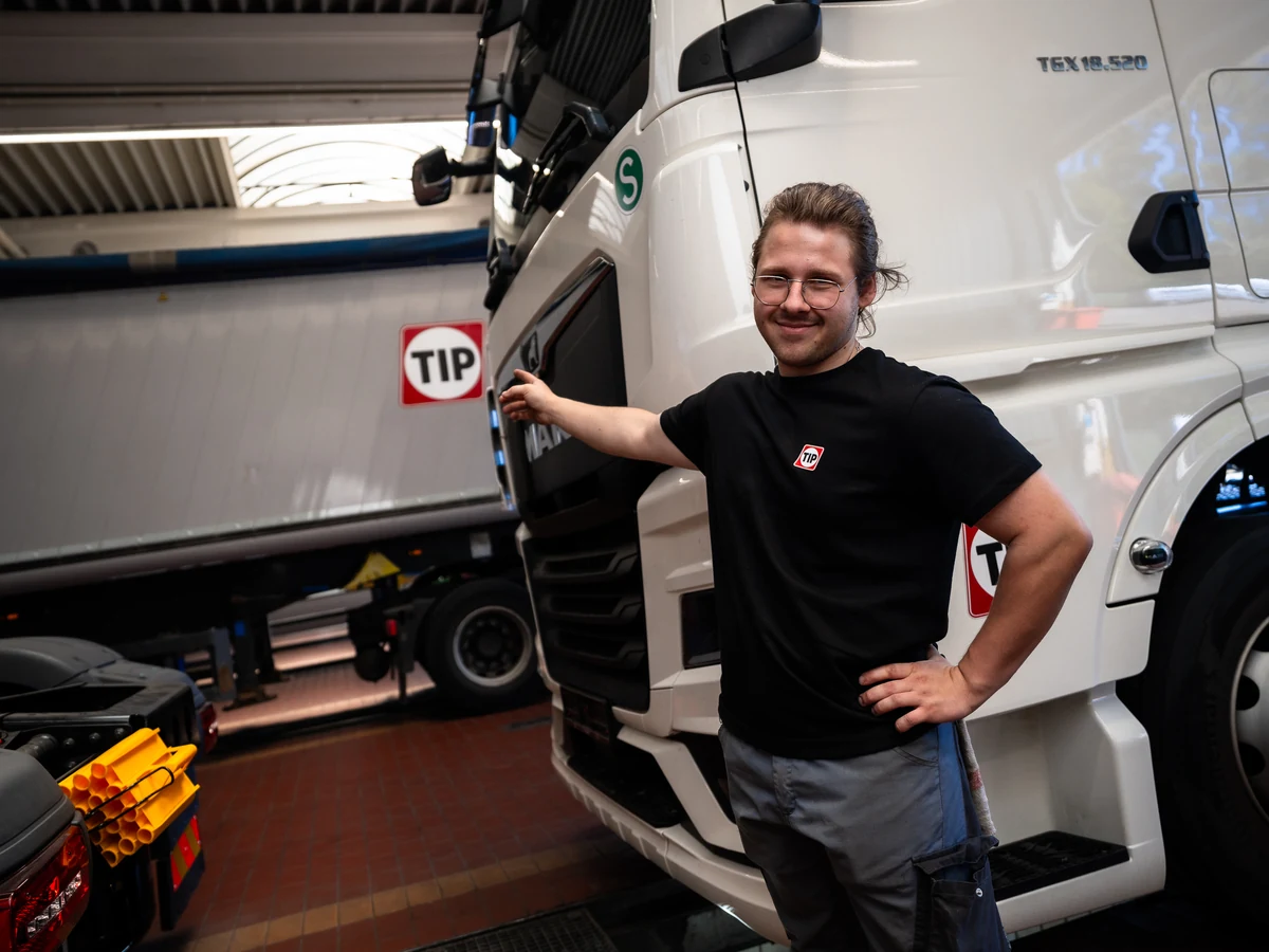 TIP Kollege zeigt auf das TIP Logo am Lkw