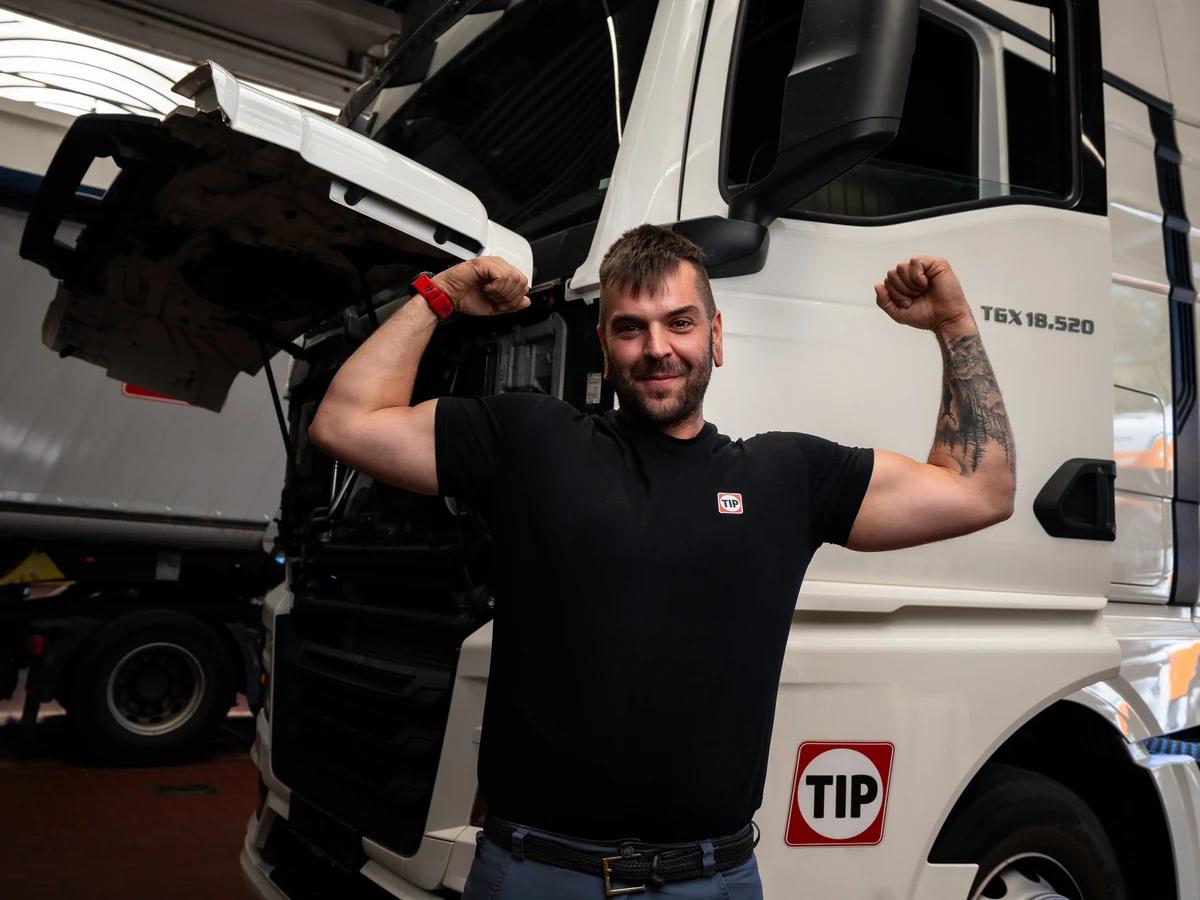 TIP Mechatroniker zeigt Muskeln vor dem Lkw