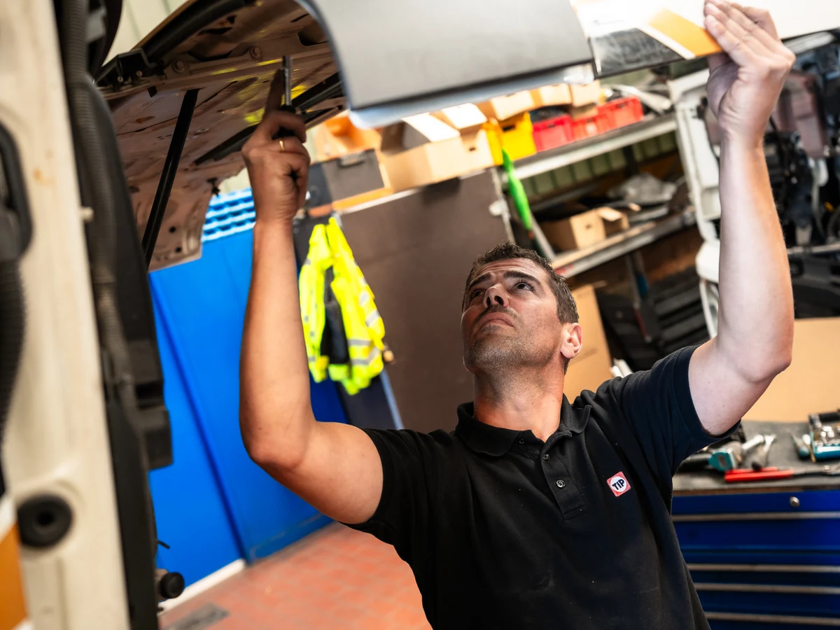 TIP Mechatroniker kontrolliert die ge&ouml;ffnete Motorhaube