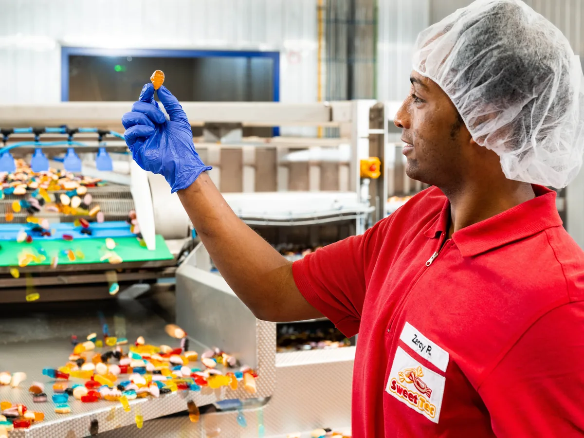 Sweet Tec Mitarbeiter prüft ein Fruchtgummi an der Produktionslinie