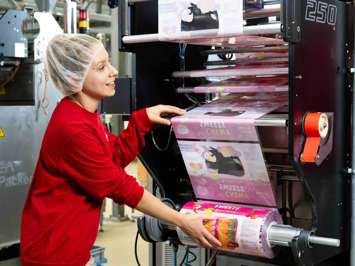 Sweet Tec Mitarbeiterin wechselt eine Folienrolle an der Schlauchbeutelmaschine