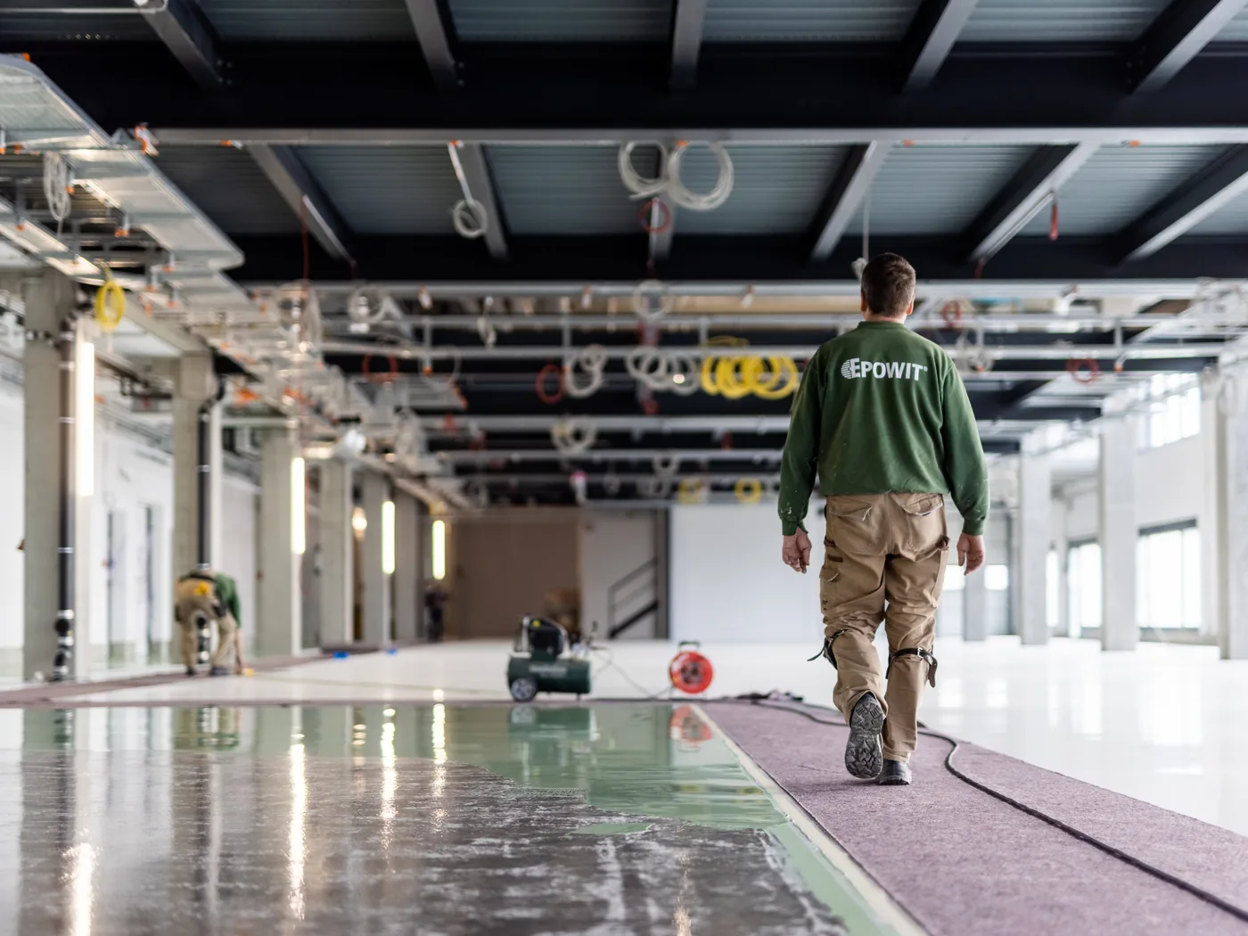 EPOWIT Mitarbeiter in einer Halle mit frisch beschichtetem Boden