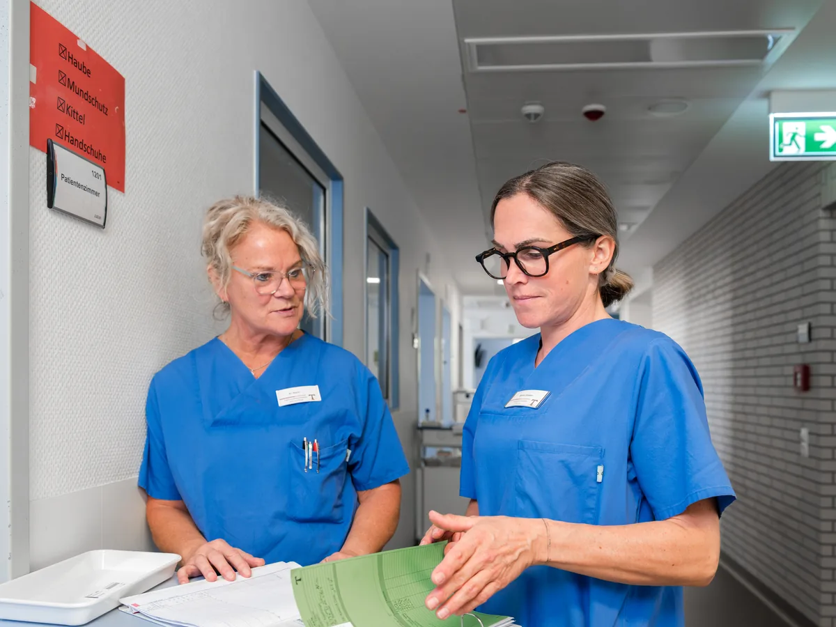 Zwei Pflegerinnen im Gespräch auf dem Flur