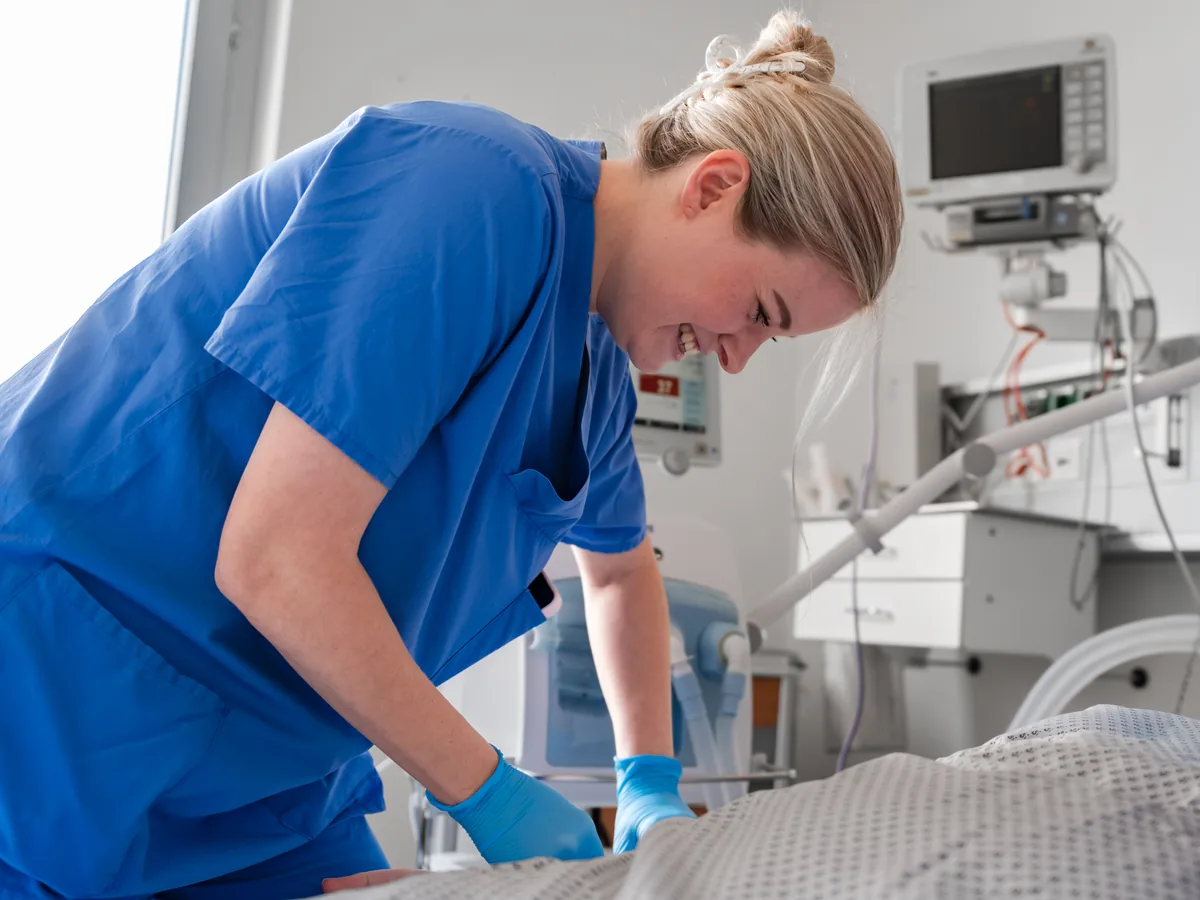 Pflegefachkraft am Patientenbett mit Beatmungsgerät
