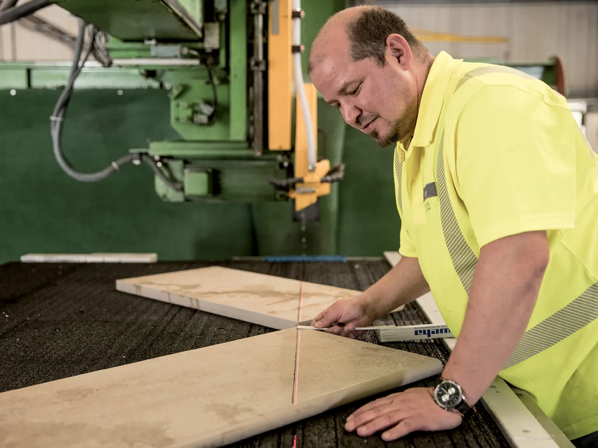 Steinmetz misst eine Platte an der CNC-Säge aus