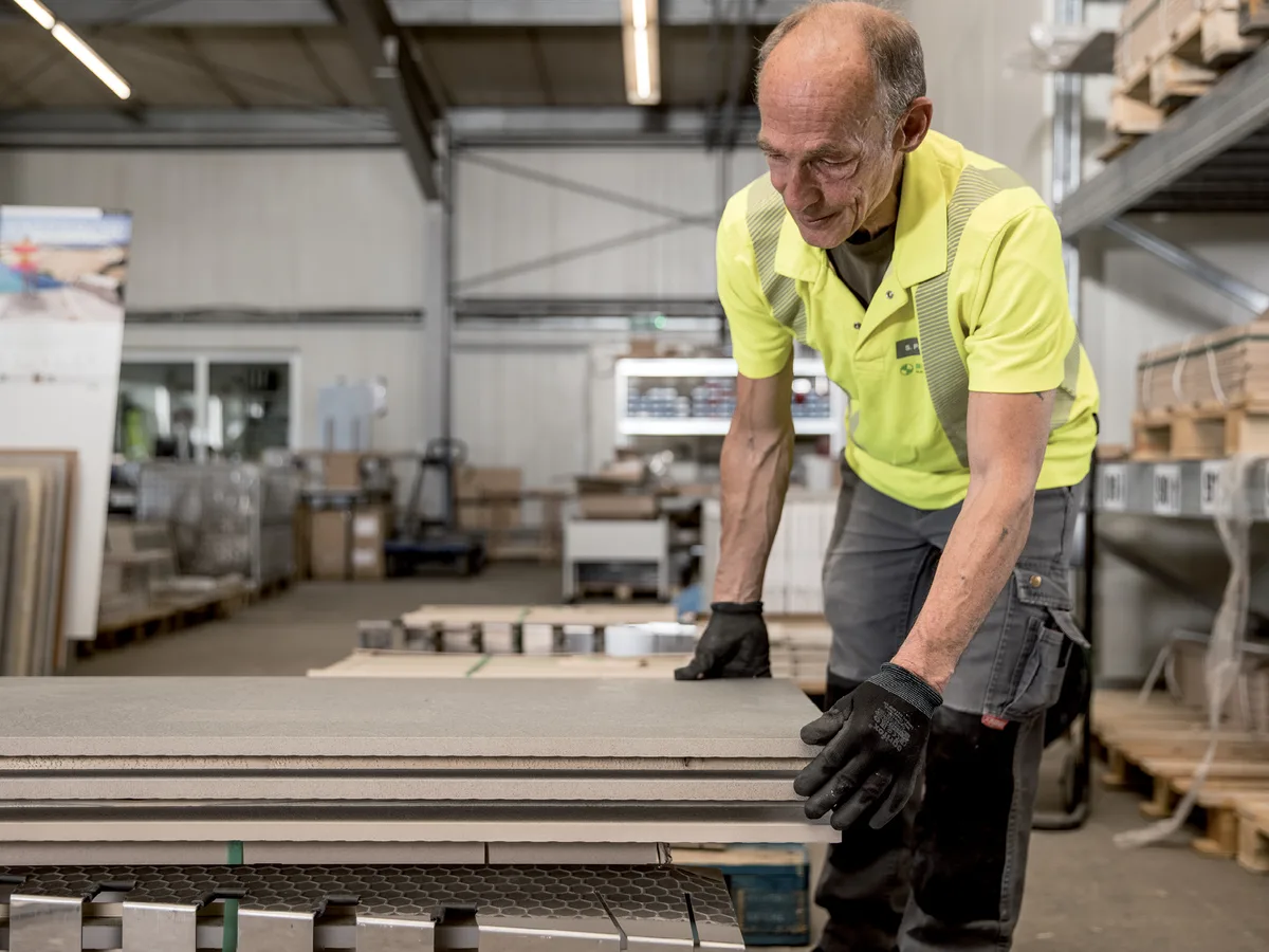 Mitarbeiter stapelt Natursteinplatten in der Halle