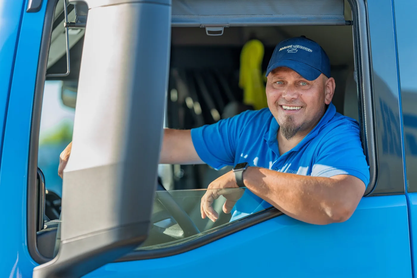 Lächelnder Nagel-Group Fahrer im blauen LKW