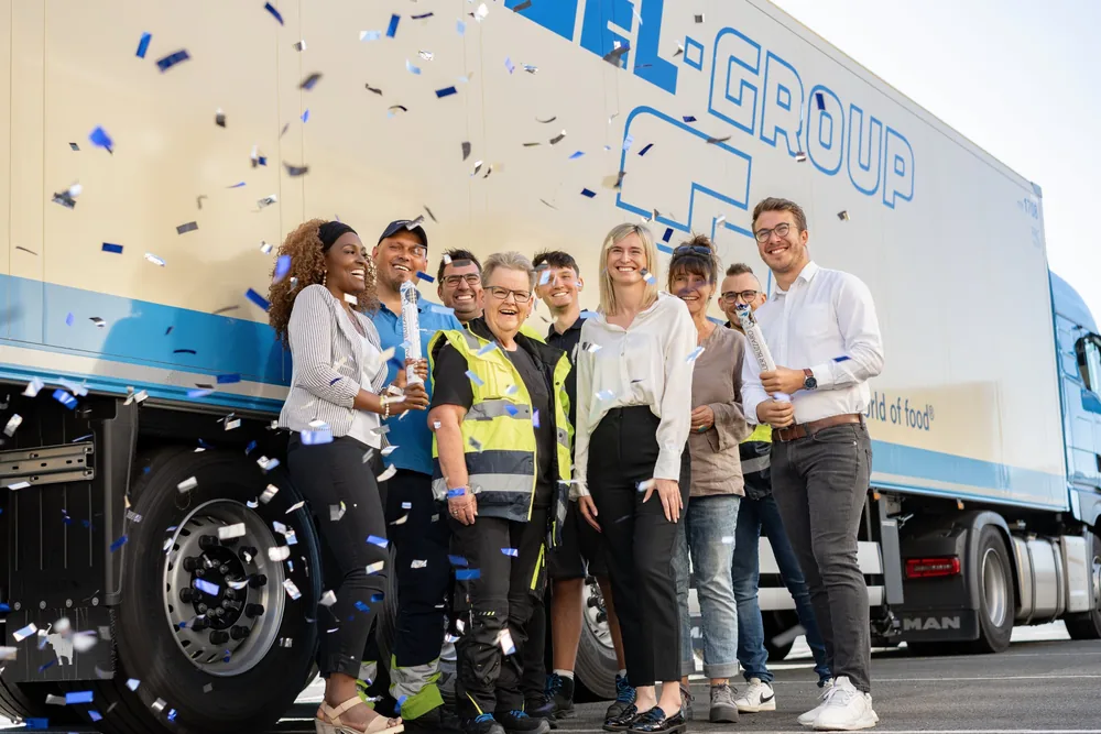 Team feiert mit Konfetti vor einem LKW