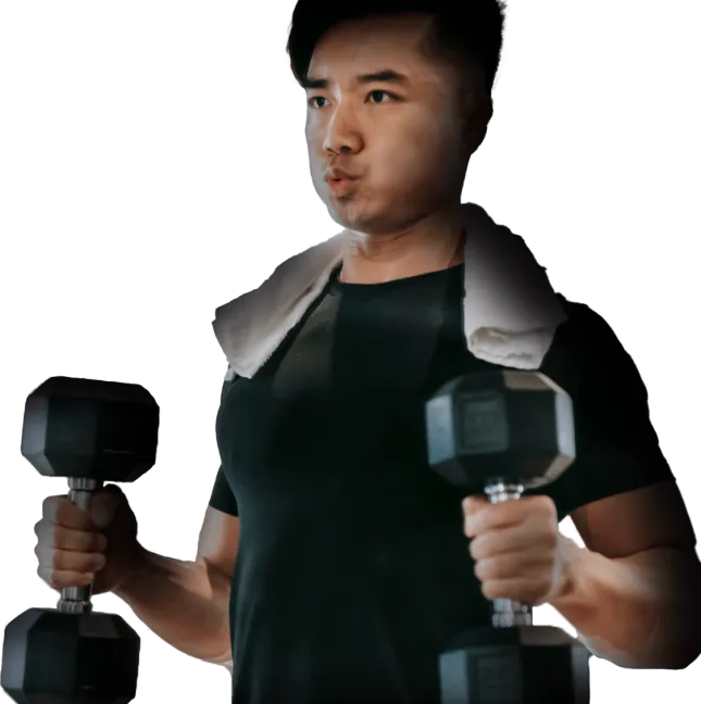 Man lifting black dumbbells with a towel draped over his shoulders, wearing a black shirt.