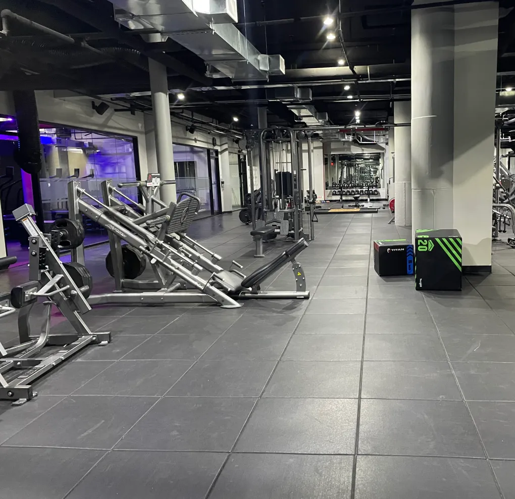 Spacious gym interior with weightlifting equipment, padded plyometric boxes, and mirrored walls.