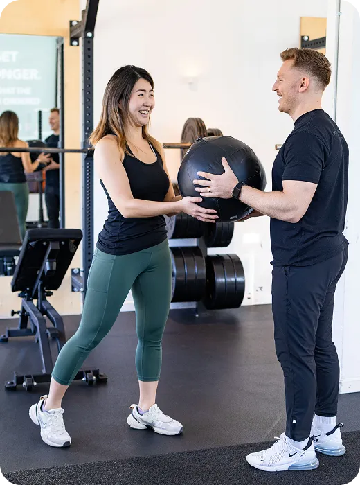 Woman and coach passing a medicine ball during a one-on-one training session