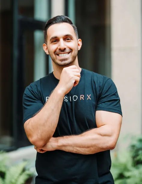 Georgio Baylouny, PT, DPT, OCS, physical therapist at PhysioRX in New York City, smiling in a PhysioRX T-shirt at the clinic