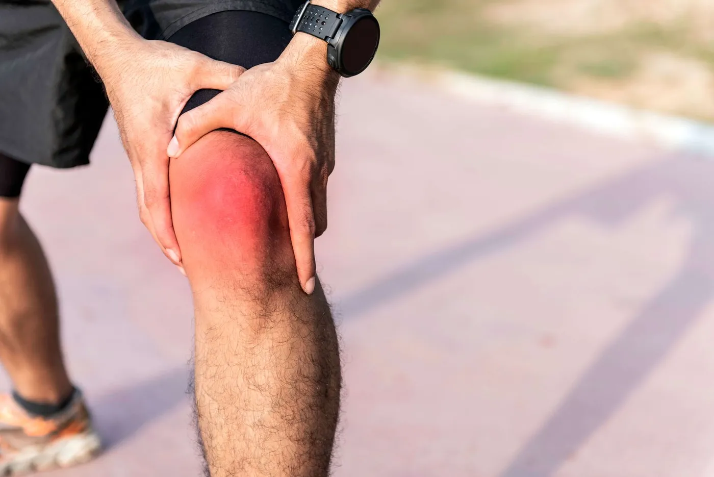Man holding his knee, highlighted red to show pain, after a run outdoors