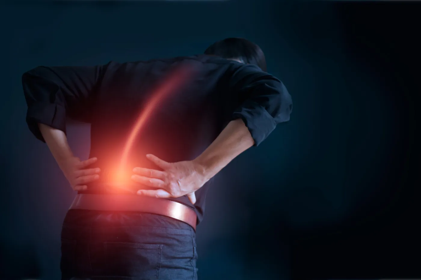 Man holding his lower back with a glowing red line showing spine pain