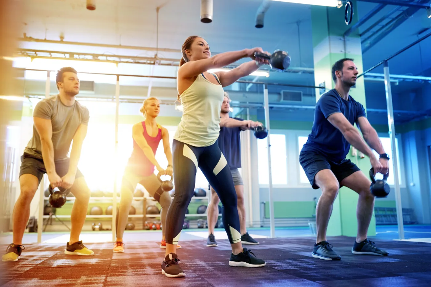 Small group doing kettlebell swings together in a bright gym