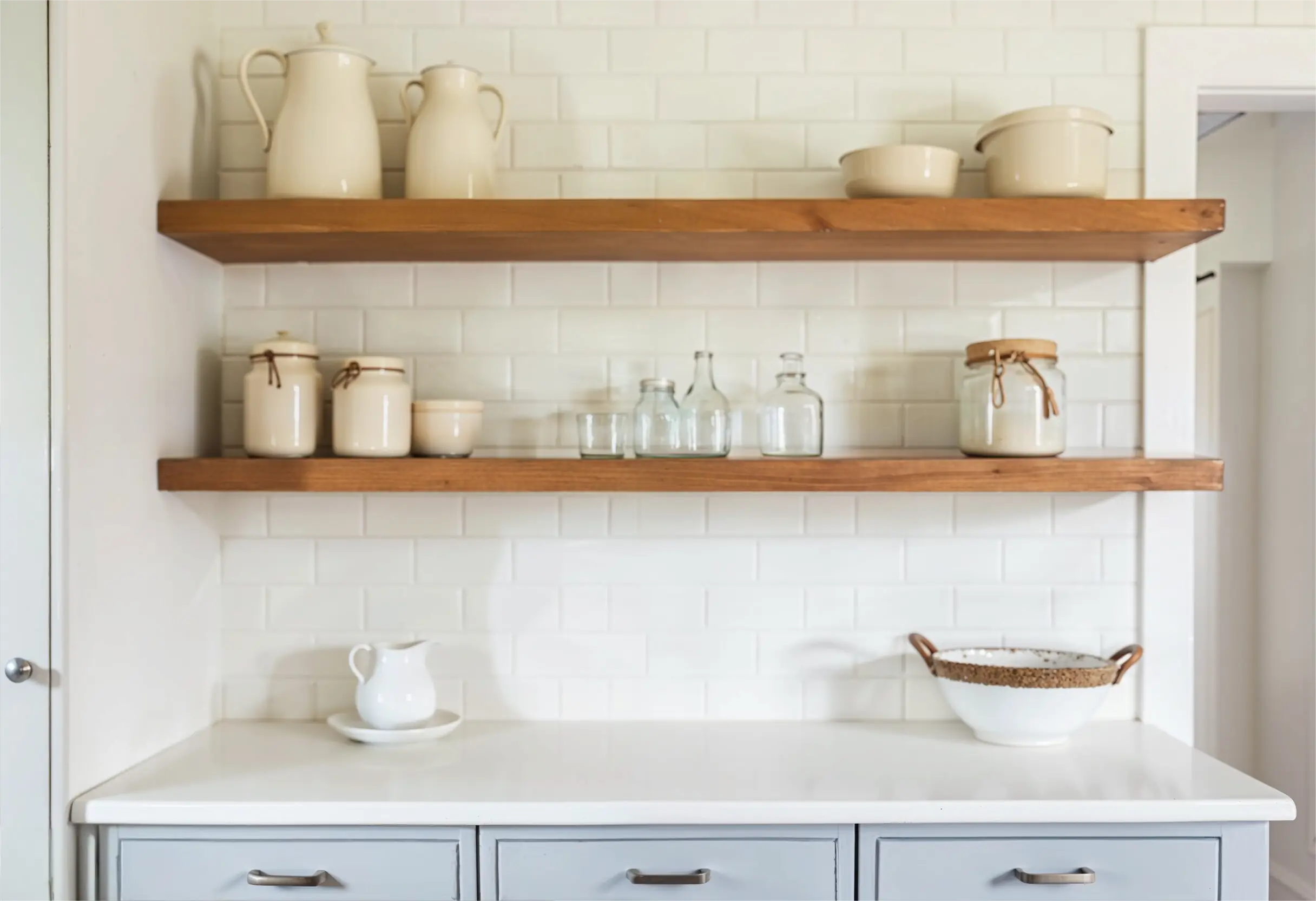 Kitchen with neutral open shelving display, soft grey cabinets, and beige ceramic dishware