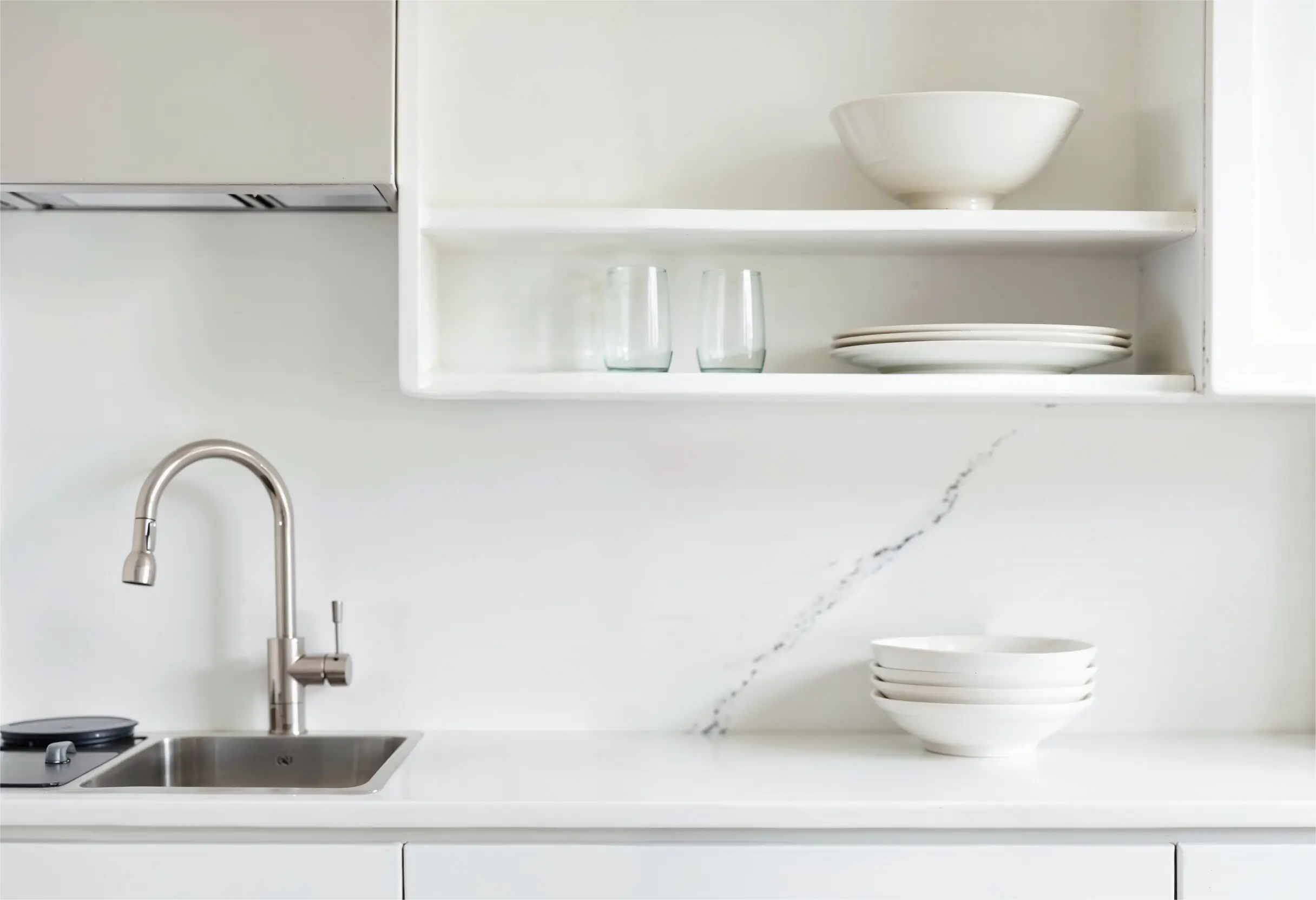 Designer kitchen with white open shelves, marble backsplash, and minimal decorative items