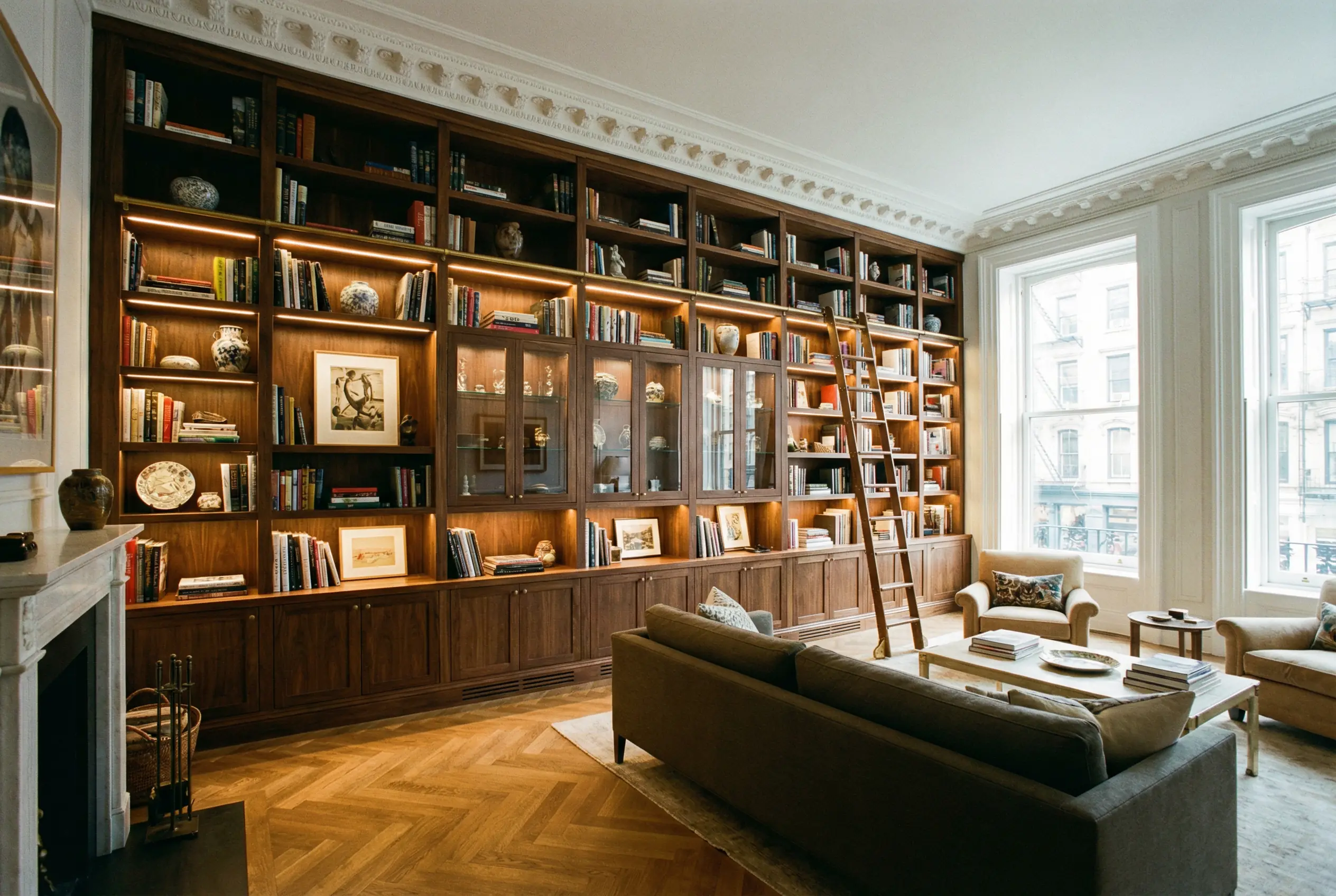 Floor-to-ceiling walnut built-in bookshelf with integrated lighting in Manhattan living room
