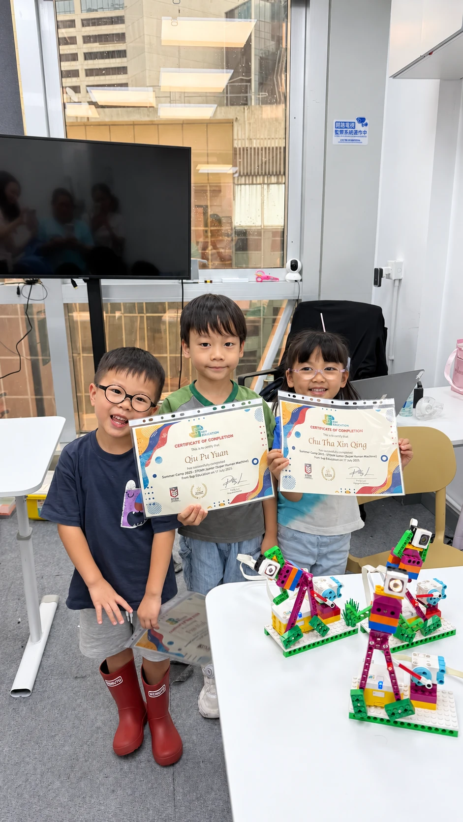 Three SUP students celebrating with their course completion certificates and LEGO creations