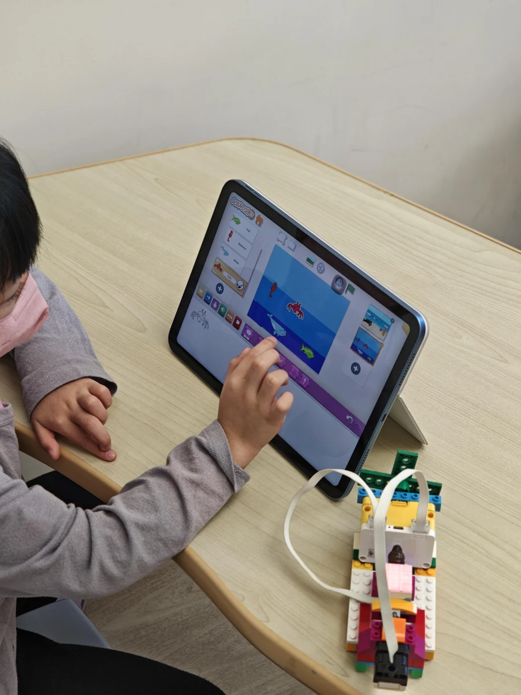 A student programming beside an ocean-themed LEGO model