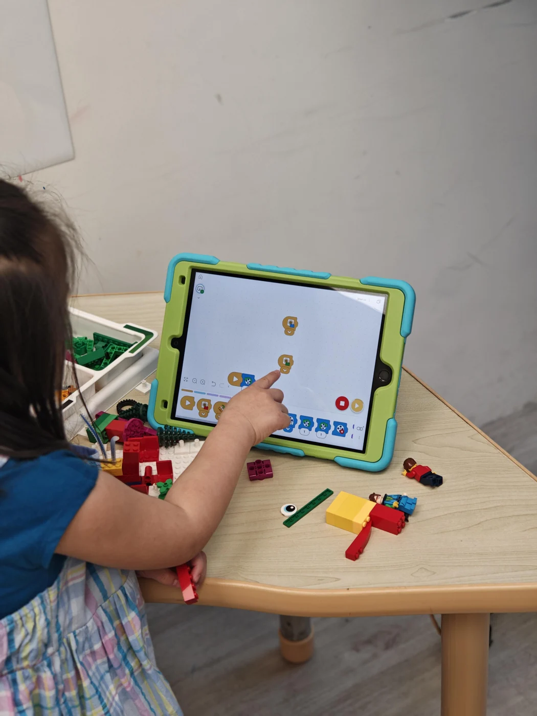 A student programming on a tablet beside LEGO pieces
